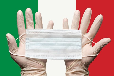 Paramedic holding respiratory face mask in two hands in white gloves on background flag of Italy.