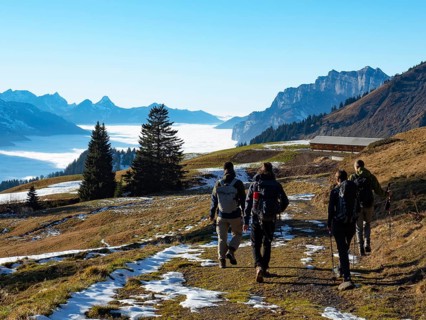 Autumn scenery with four hikers in the Swiss Alps. Very beautiful weather in the height, a big sea