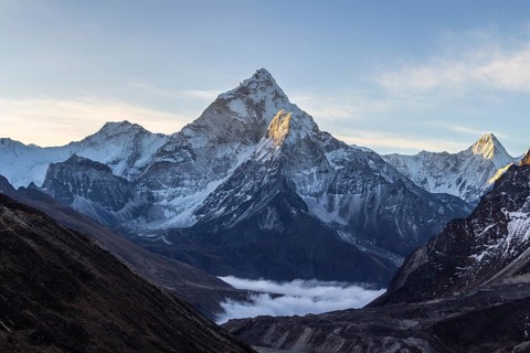 Ama Dablam mountain at sunrise and blue sky. Sun illuminates slopes. Himalayan mountains, Nepal,