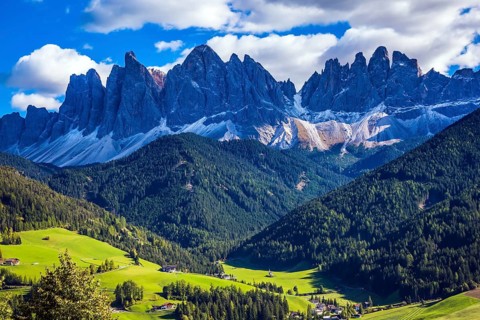 Odle mountain peaks surround the green alpine meadows of the valley. Dolomites, Val de Funes valley