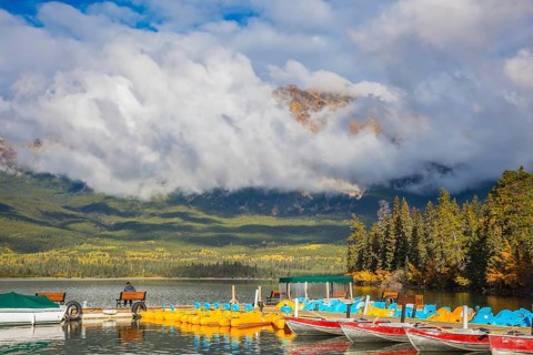 The wooden boat mooring with the moored boats. On the mooring there is elderly woman with camera.