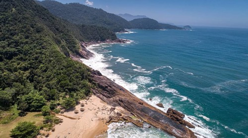 Aerial view to wonderful Green Coast shoreline with rock slabs, beach and mountains covered with