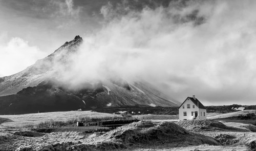 Black and white image of a Typical Icelandic winter landscape with a white small beautiful house
