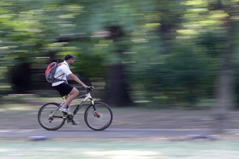 Sofia, Bulgaria - 20 August 2017 - Young man rides a bike in the park. Slow motion with blurred