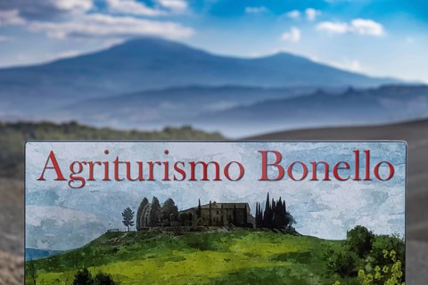 Agriturismo Bonello sign in a picturesque landscape with green meadows and mountains in the