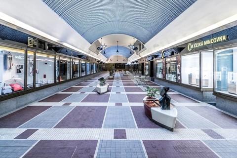 Modern shopping centre with blue ceiling and symmetrical architecture, surrounded by shops
