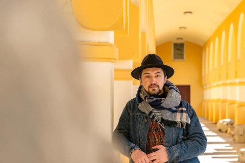 Portrait of a stylish handsome young man with a scarf outdoors. A serious man wearing a scarf, hat