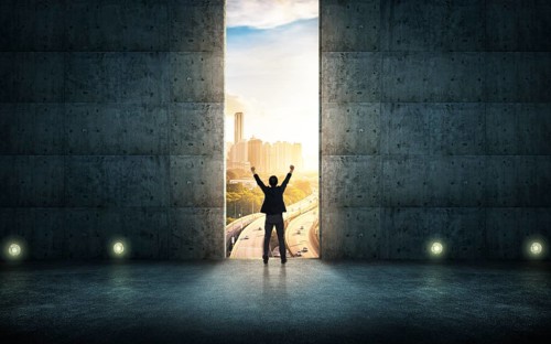 Success businessman cheering against concrete wall with huge door, sunrise scene city skyline