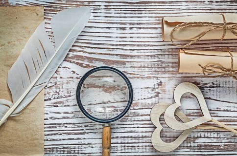 Vintage sheet paper rolls plume wooden hearts magnifier on wood board celebrations concept
