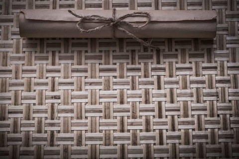Vintage rolled document with string on wicker wooden mat