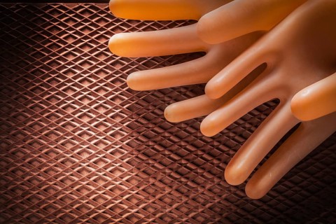 Protective insulating gloves on dielectric rubber mat
