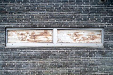 Rusted ventilation grilles in a brick wall