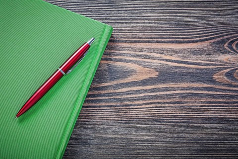 Notepad brio pen on wooden board copy space