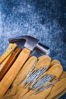 Leather safety working gloves set of construction nails wooden meter and claw hammer on scratched