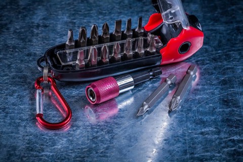 Screwdriver with muunction bit set on scratched metallic background