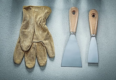 Putty knife safety gloves on concrete surface construction concept