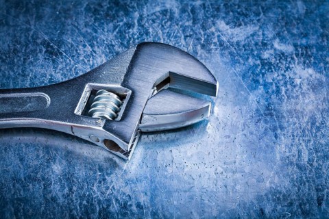 Stainless adjustable spanner on scratched metallic background top view image construction concept