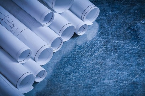 Rolled up blueprints on scratched vintage metallic background construction concept