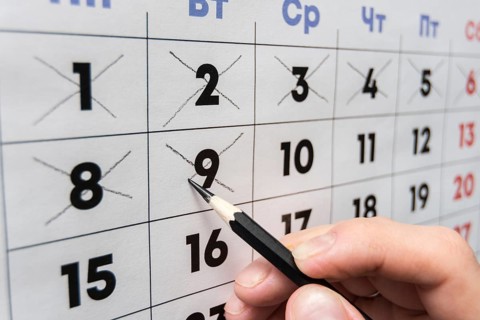 Pencil crosses out dates on the wall calendar