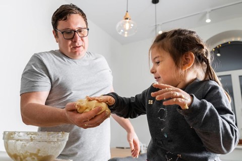 Father feeling playful with his caucasian little daughter, while preparing homemade dough for tasty