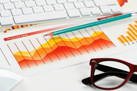 Business workplace with keyboard glasses and financial documents on table