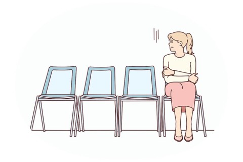 Anxious young woman sit on chair in corridor waiting or appointment. Stressed female feel worried