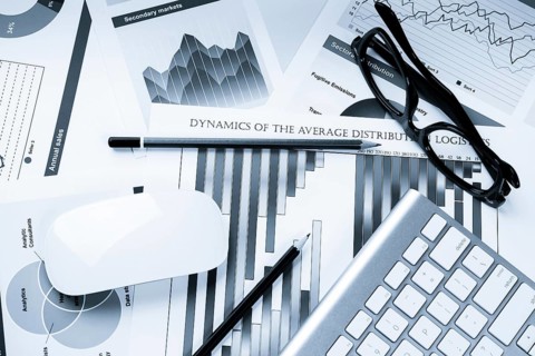 Business workplace with keyboard glasses and financial documents on table