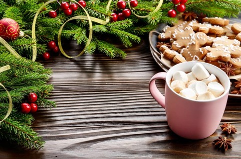Christmas background of pink mug with hot chocolate and marshmallows, spruce branch and tray with