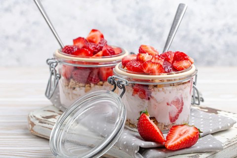 Parfait with Fresh Strawberries, Yoghurt and Crunchy Granola in Transparent Glass Mason Jars on