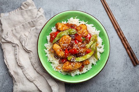 Asian sweet and sour sticky chicken with vegetables stir-fry and rice in ceramic bowl with