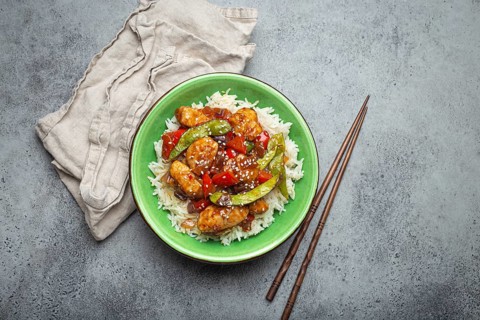 Asian sweet and sour sticky chicken with vegetables stir-fry and rice in ceramic bowl with