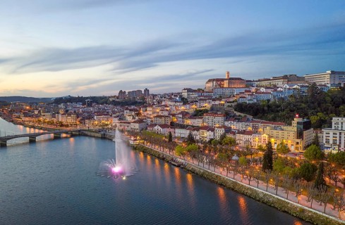 Coimbra drone aerial city view at sunset with colorful fountain in Mondego river and beautiful