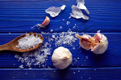 Garlic and salt spread on a blue wooden table with casual composition