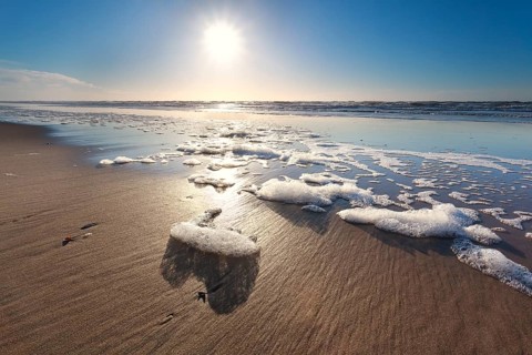 Sunshine over North sea waves on beach, Netherlands