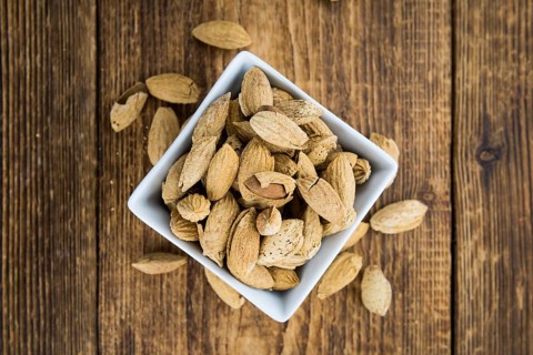 Roasted Almonds (in shell) on an old wooden table (close-up shot, selective focus)
