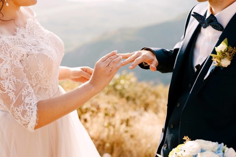 Bride in a beautiful dress puts a ring on the groom's finger.