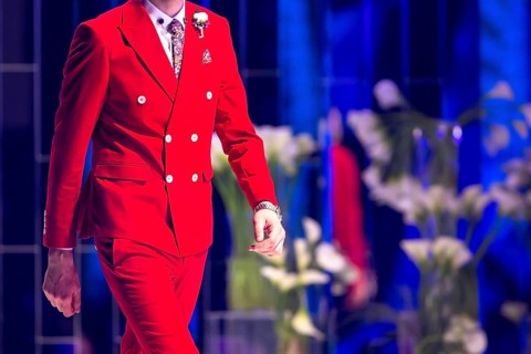 Male model walks the runway in red suit during a Fashion Show. Fashion catwalk event showing new