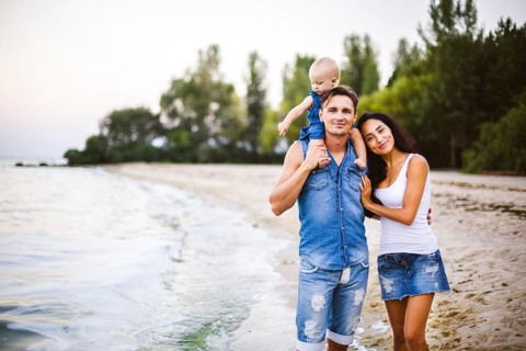 Beautiful young family on holiday with baby. The father holds the blonde girl in her arms, and the