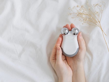 Microcurrent concept. Face massager with micro currents for home use and skincare on white bed.