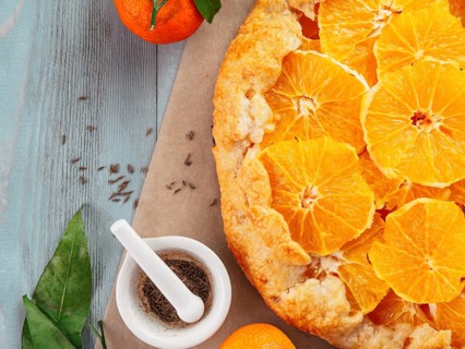 Top view of caraway and orange tart on baking paper over gray wooden table with copy space.Winter