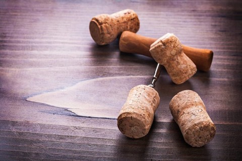 Four corks and corkscrew on vintage wooden board alcohol concept