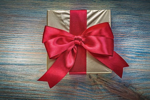 Present box with red tape on vintage wooden board holidays concept