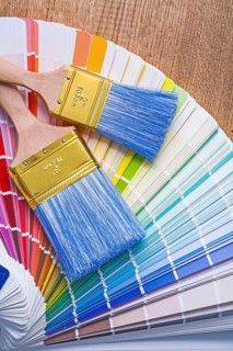 Two paintbrushes on color palette and wooden board