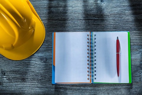 Notepad pen building helmet on wooden board