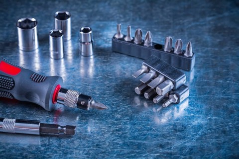 Toolset of screwdriver with stainless replaceable bits and torx on scratched metallic background