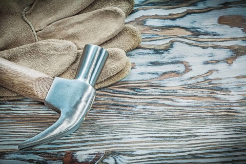 Pair of protective gloves claw hammer on wooden board