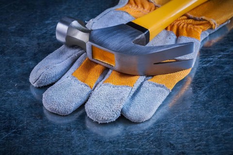 Safety gloves with claw hammer on scratched metallic background construction concept