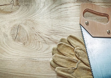 Safety gloves hacksaw on wooden board construction concept