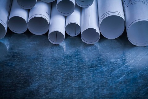 Rolls of white blueprints on scratched metallic background building and architecture concept