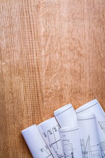 Stack of white construction rolled up blueprints on wooden boards with copyspace